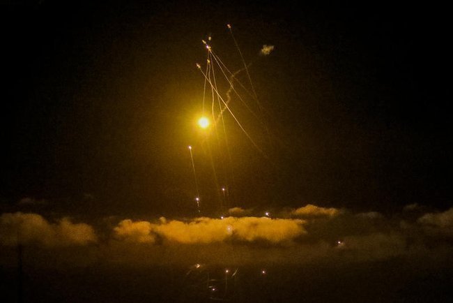 Вспышки и следы от перехваченных ракет в ночном небе