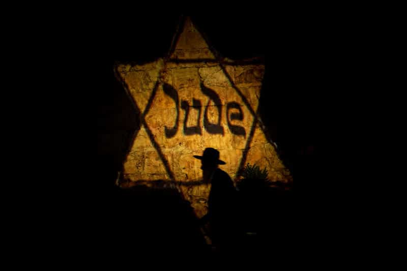 Религиозный еврей рядом с желтой звездой Давида с словом "Jude" возле стен Старого города в Иерусалиме