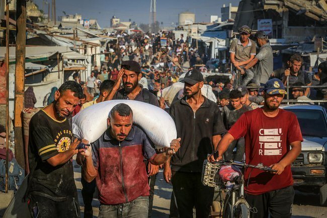 Палестинцы несут мешки с гуманитарной помощью