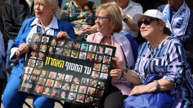 На фотографии изображены выжившие в Холокосте Двора Вайнштейн, Ирен Шахар и Ализа Гершкович с табличками имен заложников