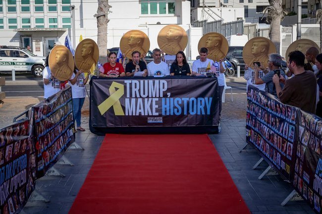 Люди с плакатом «Трамп творит историю»
