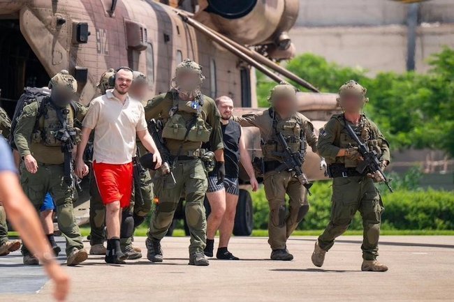 Израильские солдаты ведут освобожденного заложника