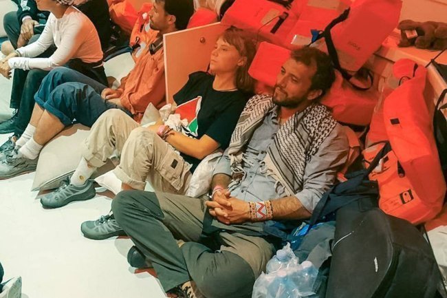 Два участника пропалестинской акции Сомуд сидят на полу в спасательных жилетах