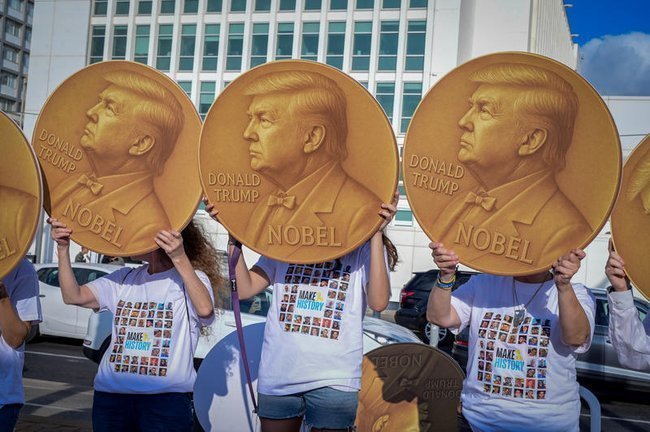 Люди держат в руках золотые медали с изображением Трампа
