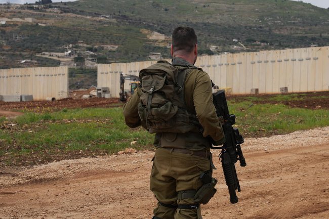 Солдат ЦАХАЛ, спиной, смотрит на границу с Ливаном