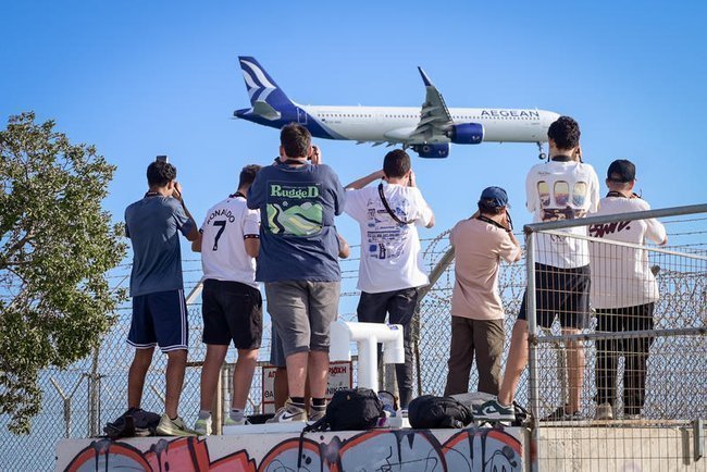 Люди фотографируют снижающийся самолет