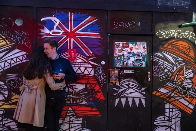 Пара обнимается на фоне граффити с британским флагом