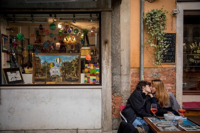 Молодая пара целуется, сидя в баре в Венеции, Италия
