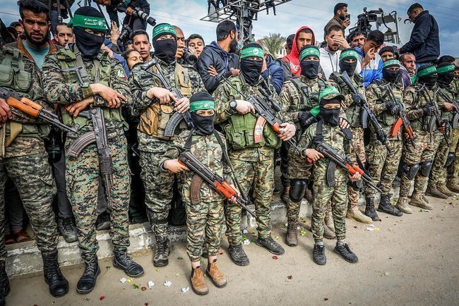 Боевики ХАМАСа в униформе и с оружием стоят в ряд, среди них дети
