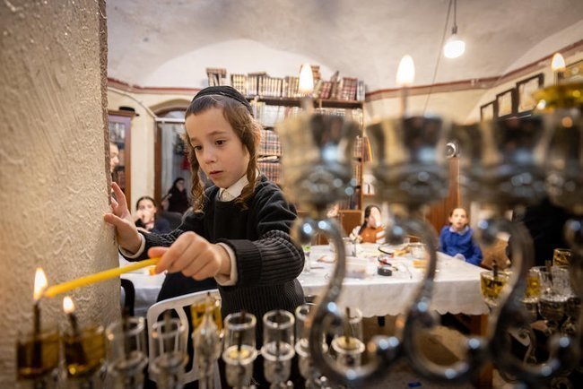 Мальчик зажигает свечи на Хануку