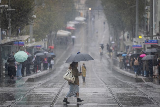 Женщина под зонтом идет по Иерусалиму