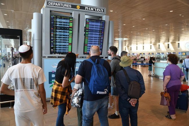Пассажиры аэропорта имени Бен-Гуриона изучают табло вылетов.