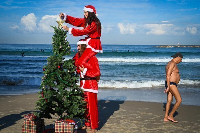 Израильтяне в костюмах Санта-Клауса на пляже в Тель-Авиве