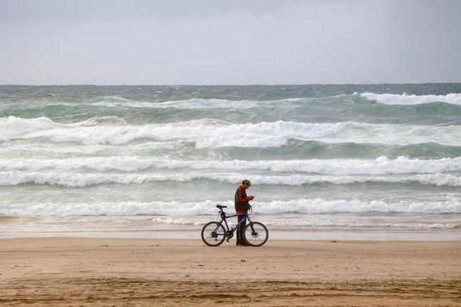Человек с велосипедом на фоне штормового моря