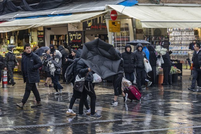 Люди под дождем и с зонтами на иерусалимской улице
