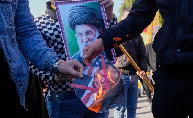 Сторонники иранского режима сжигают фотографию Дональда Трампа на демонстрации в Ираке.