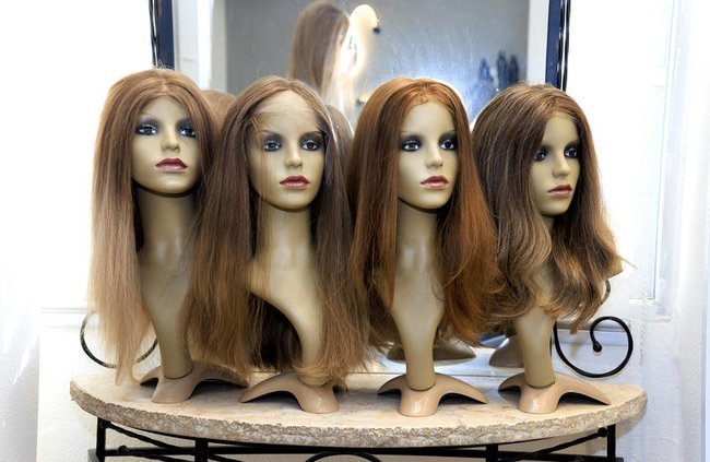 Женские парики на витрине салона.