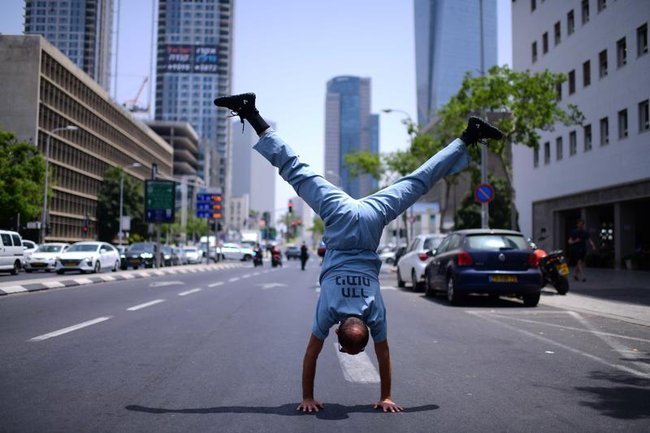 Молодой парень в медицинской одежде стоит на руках посреди улицы