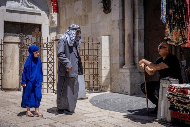 Арабский мужчина и девочка в хиджабе идут по Старому городу Иерусалима