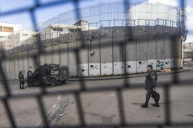 Израильские силы безопасности устанавливают бетонные заграждения, чтобы перекрыть дорогу возле разделительной стены в восточноиерусалимском районе