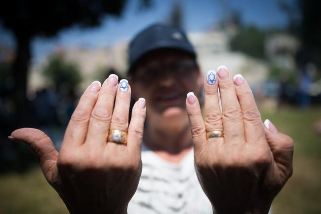 Женщина показывает маникюр с израильским флагом