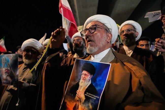 Иракские шиитские духовные лидеры держат портрет аятоллы Али Хаменеи во время протеста против ударов США и Израиля по Ирану