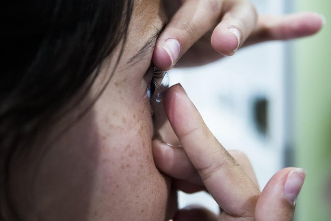 Девушка вставляет контактную линзу.