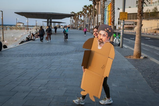 Жительница Тель-Авива несет картонную фигуру Моджтабы Хаменеи.