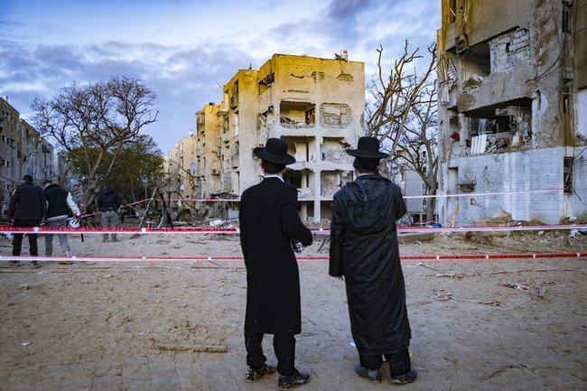 Жители Арада у места падения иранской ракеты в субботу, 21 марта.