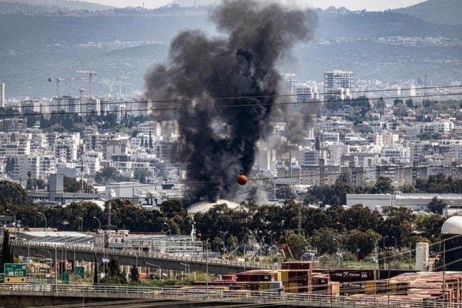 Над нефтеперерабатывающими заводами в Хайфе, на севере Израиля, поднимается дым после ракетного удара, нанесенного Ираном по Израилю 30 марта
