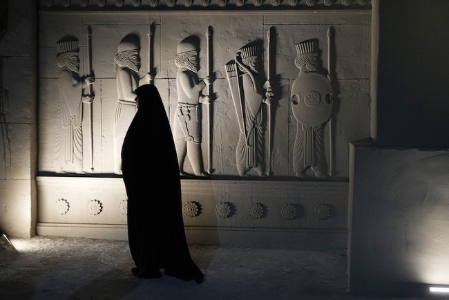 Женщина в чадре проходит мимо модели древнего Персеполя — столицы Персидской империи — на выставке в Тегеране