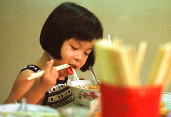 Молодая вьетнамка завтракает супом с рисовой лапшой — «фо» — в одной из уличных лавок Ханоя