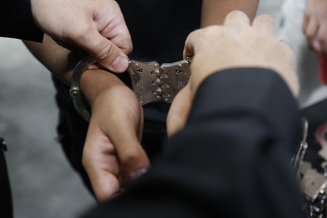 крупным планом руки, на которые надевают наручники