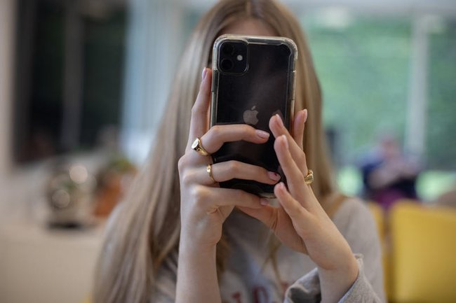 Подросток смотрит в свой смартфон во время ужина