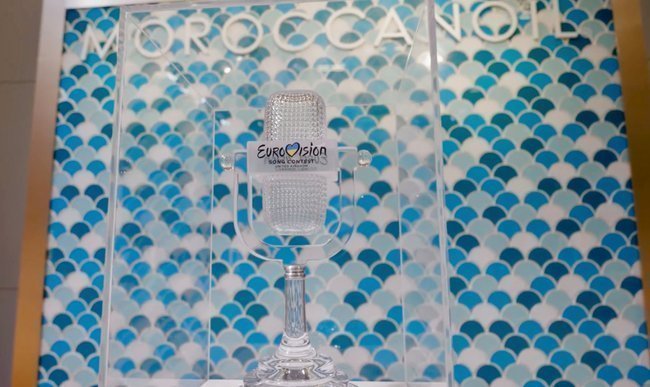 Кубок Евровидения на фоне логотипа Moroccanoil